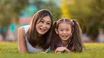 Free photo front view asian mother and daughter staying on grass together