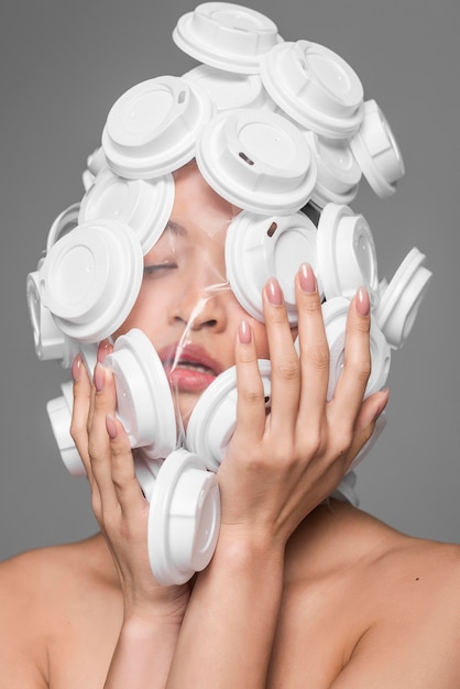 Free photo front view asian woman face being covered in white plastic lids