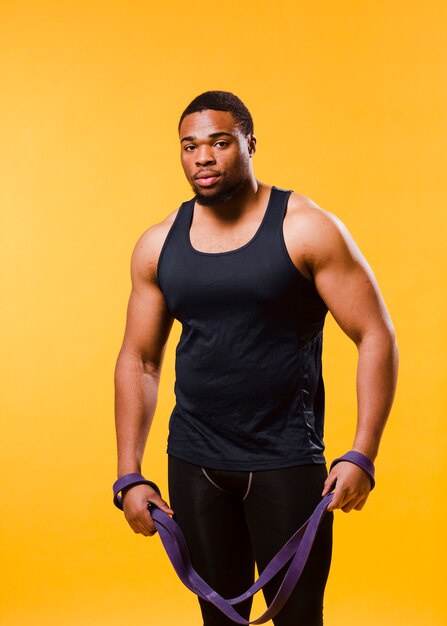 Front view of athletic man in gym outfit with resistance band