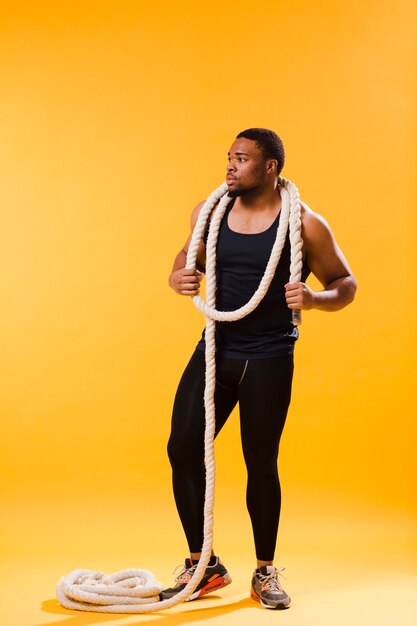 Front view of athletic man in gym outfit with rope