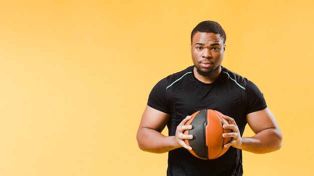 Free photo front view of athletic man holding basketball