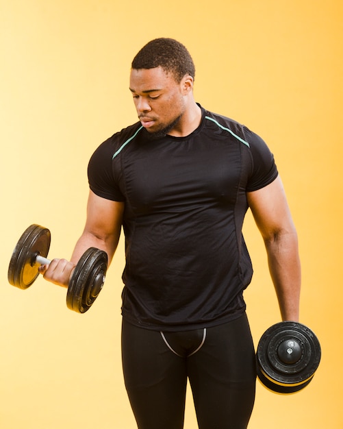 Front view of athletic man holding weights in gym outfit