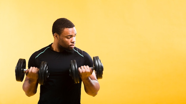 Front view of athletic man holding weights with copy space