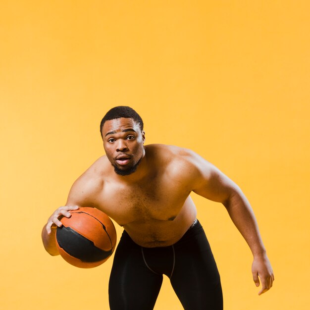 Front view of athletic man playing basketball shirtless