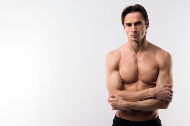 Front view of athletic man posing shirtless with copy space