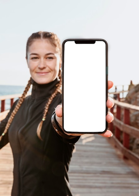 Free photo front view of athletic woman holding smartphone