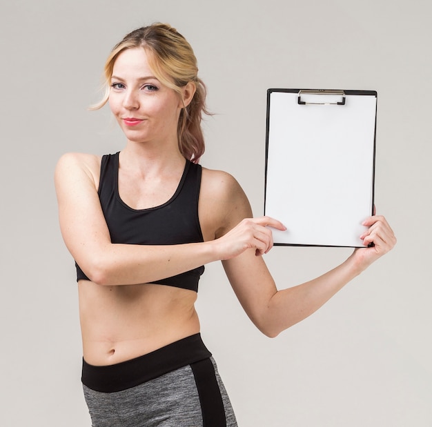 Front view of athletic woman smiling and holding notepad