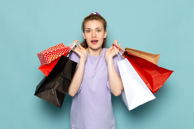 Free photo a front view attractive female in blue shirt-dress holding shopping packages on blue