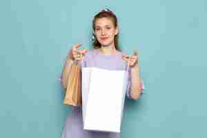 Free photo a front view attractive female in blue shirt-dress holding shopping packages on blue