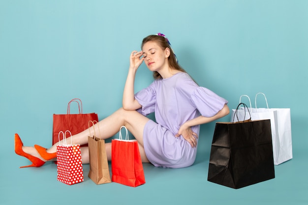 ショッピングパッケージを押しながら青に座っている青いシャツドレスで正面の魅力的な女性