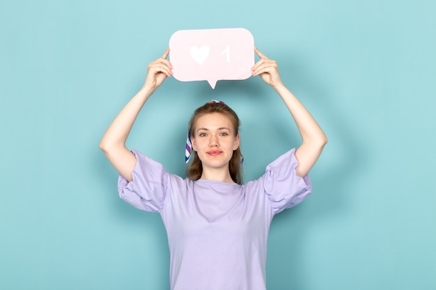 A front view attractive female in blue shirt-dress holding white sign on blue