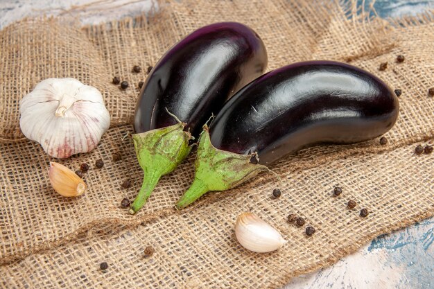 Front view aubergines garlic black pepper on straw tablecloth