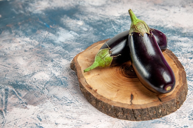 Free photo front view aubergines on tree wood board on blue-white background free place