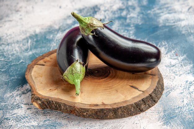 Front view aubergines on tree wood board on blue-white