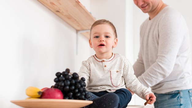 Free photo front view of baby with father in the kitchen