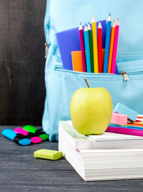 Вид спереди обратно в школу канцелярских товаров с яблоком и красочными карандашами