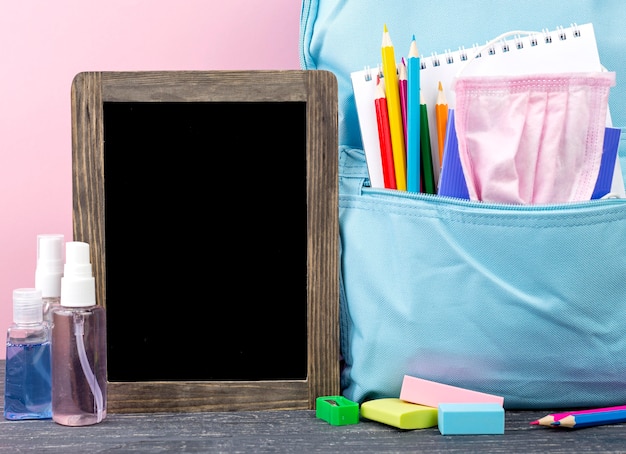 Front view of back to school stationery with backpack and blackboard