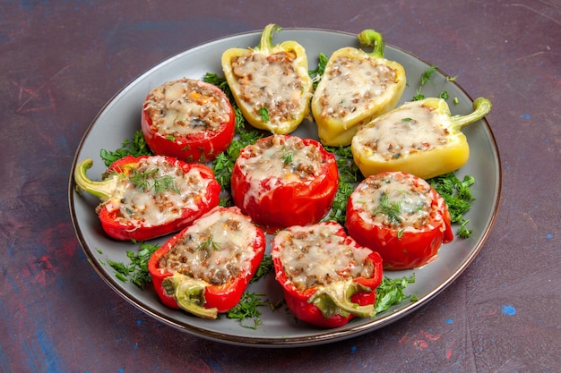 Free photo front view baked bell-peppers with cheese greens and meat inside plate on dark background bake dinner dish food meal