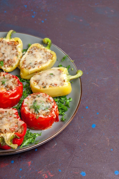 Foto gratuita vista frontale peperoni al forno con verdure al formaggio e carne all'interno del piatto su sfondo scuro cibo cuocere il piatto della cena