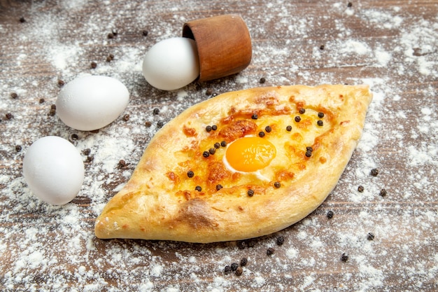 Foto gratuita vista frontale pane all'uovo al forno con farina sulla superficie marrone pasta pane all'uovo bun colazione