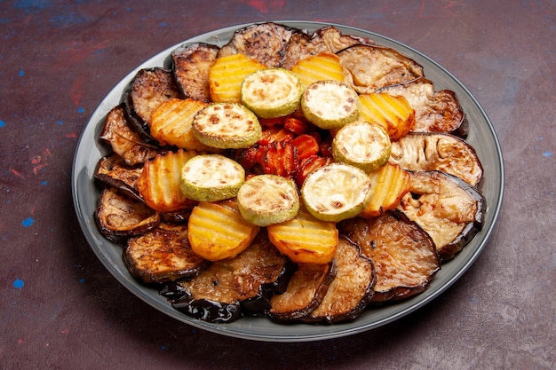 Вид спереди запеченные овощи, картофель и баклажаны, только что вынутые из духовки в темном месте