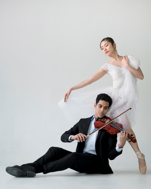 Free photo front view of ballerina and musician playing violing