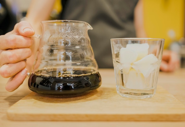 Front view of barista holding coffee pot with glass of ice