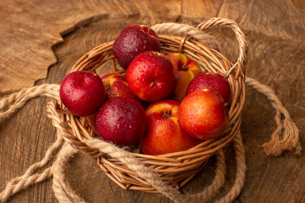 Front view of basket with peaches and plums on the wooden desk