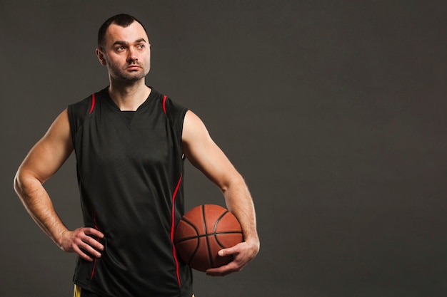 Free photo front view of basketball player posing with ball and copy space