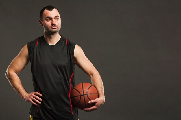 Front view of basketball player posing with ball and copy space