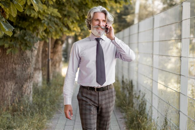 Front view bearded mature male talking on the phone