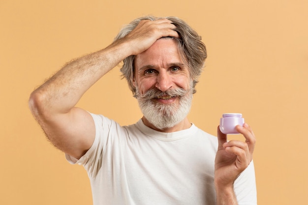 Front view of bearded senior man holding hair gel