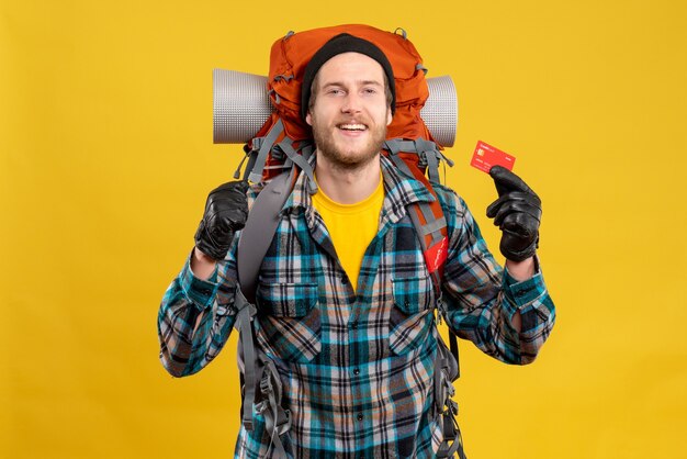 Front view of bearded young man with backpacker holding credit card