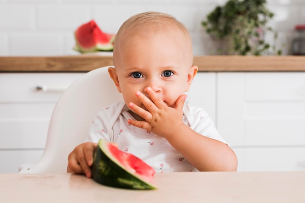 Free photo front view of beautiful baby eating watermelon