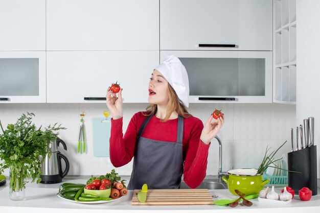 Вид спереди красивая женщина-повар в фартуке с помидорами