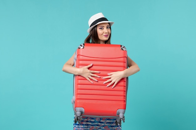 Front view beautiful female holding red bag and preparing for trip on blue space