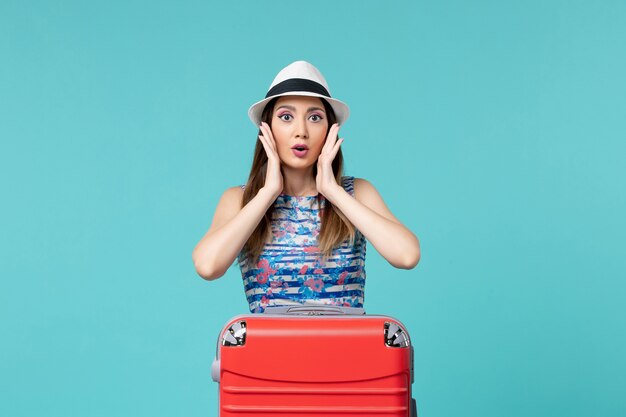 Front view beautiful female preparing for vacation with her red bag on light blue space