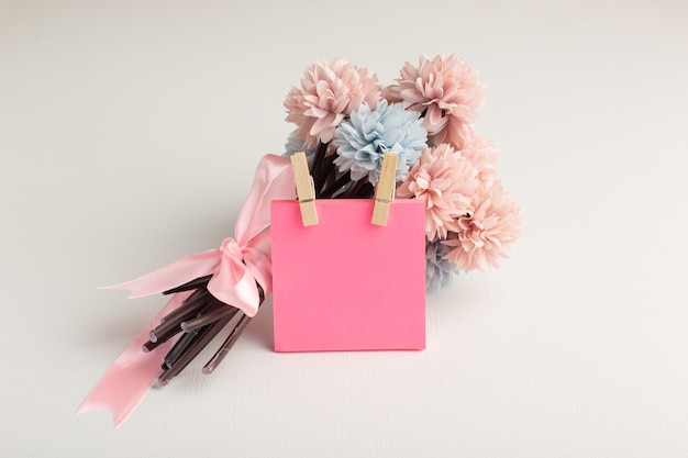 Free photo front view beautiful flowers with pink sticker on white surface