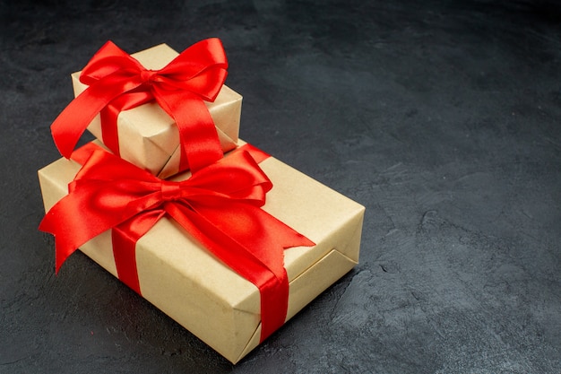 Front view of beautiful gifts with red ribbon on the right side on dark background