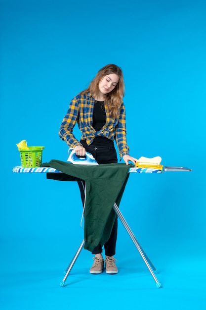 Front view of beautiful girl ironing the blouse on board in the laundry room