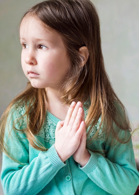 Вид спереди красивая маленькая девочка молится