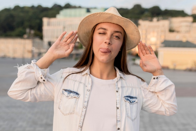 Front view of beautiful woman posing silly with hat while traveling