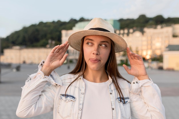 Front view of beautiful woman posing with hat while traveling alone