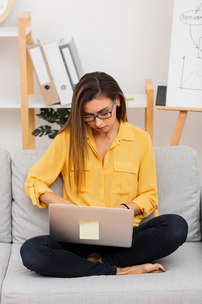 Front view beautiful woman sitting on sofa with her laptop