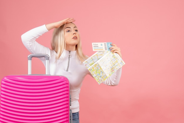 Front view beautiful woman with pink suitcase holding map and ticket