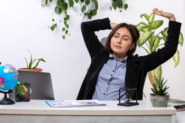 A front view beautiful young businesswoman in black jacket and blue shirt sneezing in front of table business job office