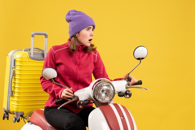 Front view bemused young woman on moped looking at something