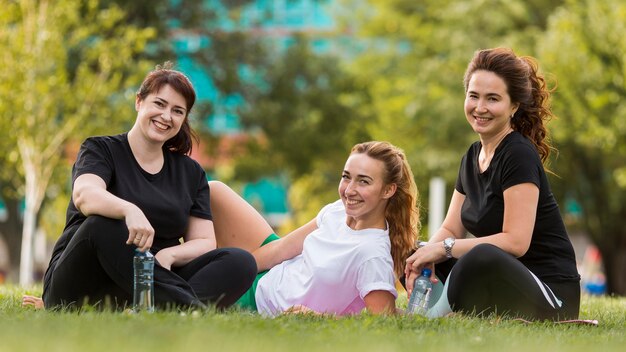 Front view best friends sitting on grass while wearing sportswear clothing