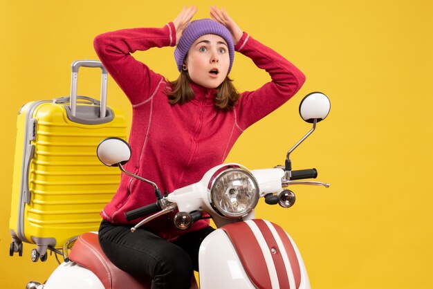 Front view bewildered young girl on moped holding head looking at something