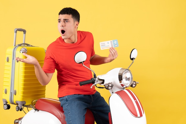 Front view bewildered young male in casual clothes on moped holding ticket